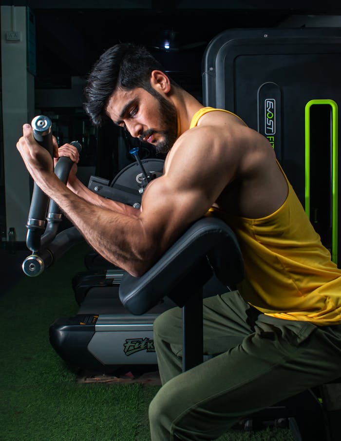 services-01 Muscular man in a gym performing bicep curls on a machine, showcasing strength and dedication.